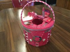 a pink basket sitting on top of a wooden table