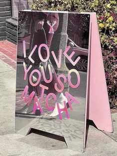 a sign on the sidewalk that says i love you so much and has pink writing