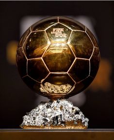 a golden soccer ball sitting on top of a wooden table