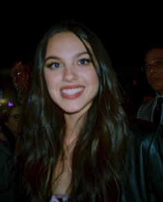 a woman with long hair and blue eyes smiles at the camera while standing in front of an audience