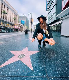 a woman kneeling down in front of a star on the hollywood walk of fame with her hands out