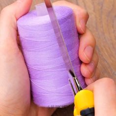 someone is using scissors to cut the thread off of a purple yarn ball with a pair of yellow handled scissor