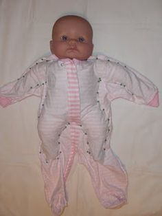 a baby doll laying on top of a white sheet