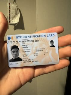 a person holding up a new york identification card