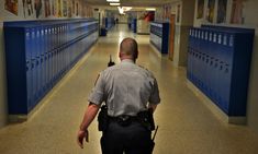 a police officer walking down a hallway with blue lockers