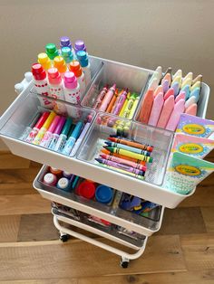 the cart is full of markers, crayons, and other crafting supplies