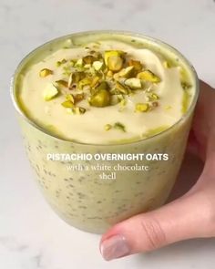 there is a hand holding a cup with pistachio overnight oats in it