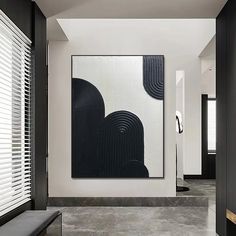 a black and white abstract painting hangs on the wall next to a bench in a hallway