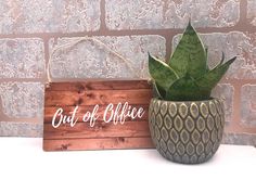 a potted plant sitting next to a sign that says out of office