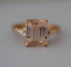 an orange and white diamond ring sitting on top of a gray surface with two diamonds around it