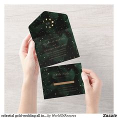 a person holding up two green and gold foiled wedding cards in front of the camera