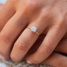 a woman's hand with a diamond ring on her left hand and the middle finger