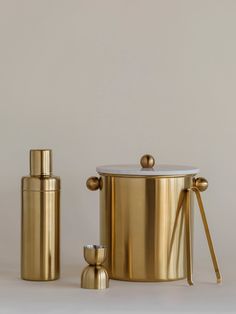 a gold canister and two cups on a white surface with the lid open to reveal something