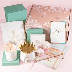 the contents of a birthday gift box on a pink background with candles and other items