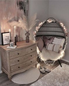 a bedroom with a bed, dresser and hanging birdcage decorated with lights in the corner