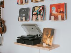 a record player sitting on top of a wooden shelf next to a wall with books