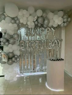 a birthday party with balloons and silver foil decorations on the wall, along with a cake stand