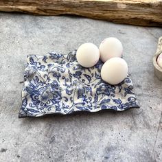 three eggs sitting on top of a blue and white cloth next to an egg holder