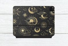 a black and gold phone case with the sun, moon and clouds pattern on it