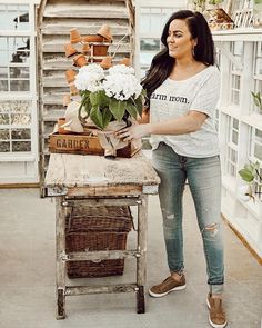 a woman standing next to a table with flowers on it