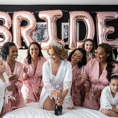 a group of bridesmaids in pink robes toasting champagne