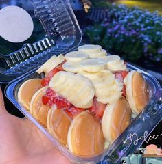 a plastic container filled with bananas and strawberries