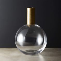 a clear glass bottle sitting on top of a table next to a brown object with a gold cap