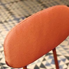 an orange chair sitting on top of a checkered floor