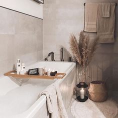 a white bath tub sitting next to a wooden shelf filled with candles and other items