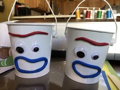 two plastic buckets with faces painted on them