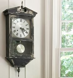 an old clock hanging on the wall next to a window