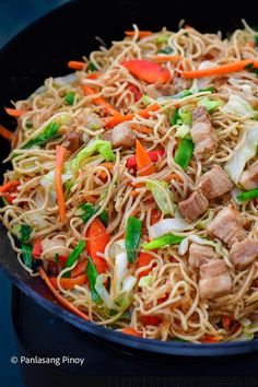 a wok filled with noodles, meat and veggies