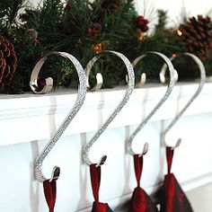 three christmas stockings hanging from hooks on a mantel