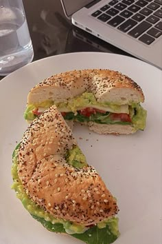 a sandwich cut in half sitting on top of a white plate next to a laptop