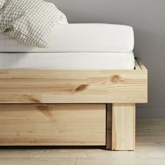 a wooden bed with white sheets and pillows