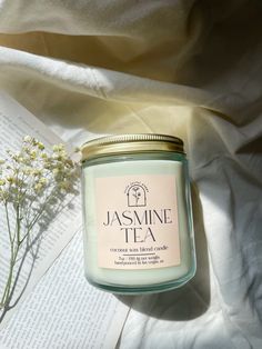 a jar of tea sitting on top of a table next to a book and flowers