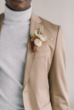 a man wearing a tan suit and flower boutonniere