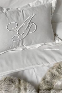 the monogrammed pillow is on top of the white bedding with furs