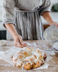 a woman is spreading icing on a pastry