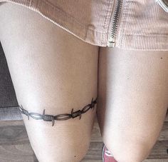 a woman's legs with barbed wire tattoo on the side of her leg,