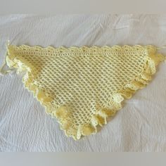 a yellow crocheted triangle on top of a white sheet