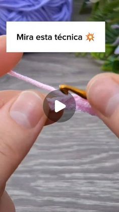 a person is holding a pink string with a small yellow object in the middle of it