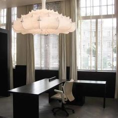 an office with black and white furniture and large chandelier hanging from the ceiling