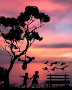 two children are playing in front of a tree with birds flying around them at sunset