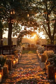 an outdoor ceremony with candles and flowers on the ground in front of trees at sunset