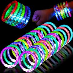 glow bracelets and wristbands are shown in the dark with one person's hand next to them