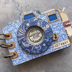 a blue and white camera sitting on top of a cement floor next to a wall