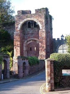 an old brick building with a gate in front of it and bushes on either side