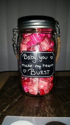 a jar filled with lots of candy sitting on top of a table next to a cell phone