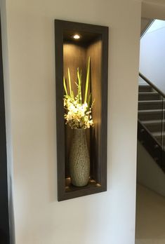 there is a vase with flowers in it sitting on the wall next to some stairs